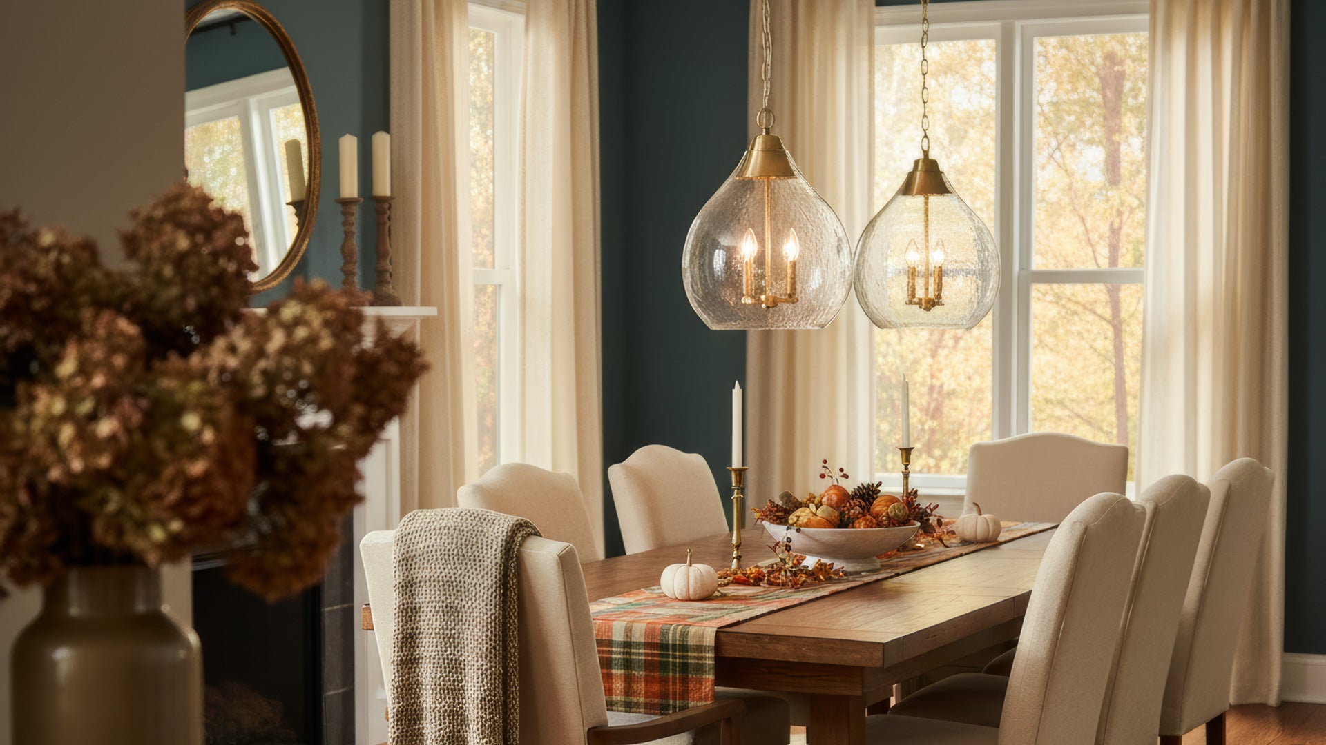 Dining room with a wooden table, chairs, and decorative elements for fall with Ariella 3-Light pendant in brushed champagne brass.