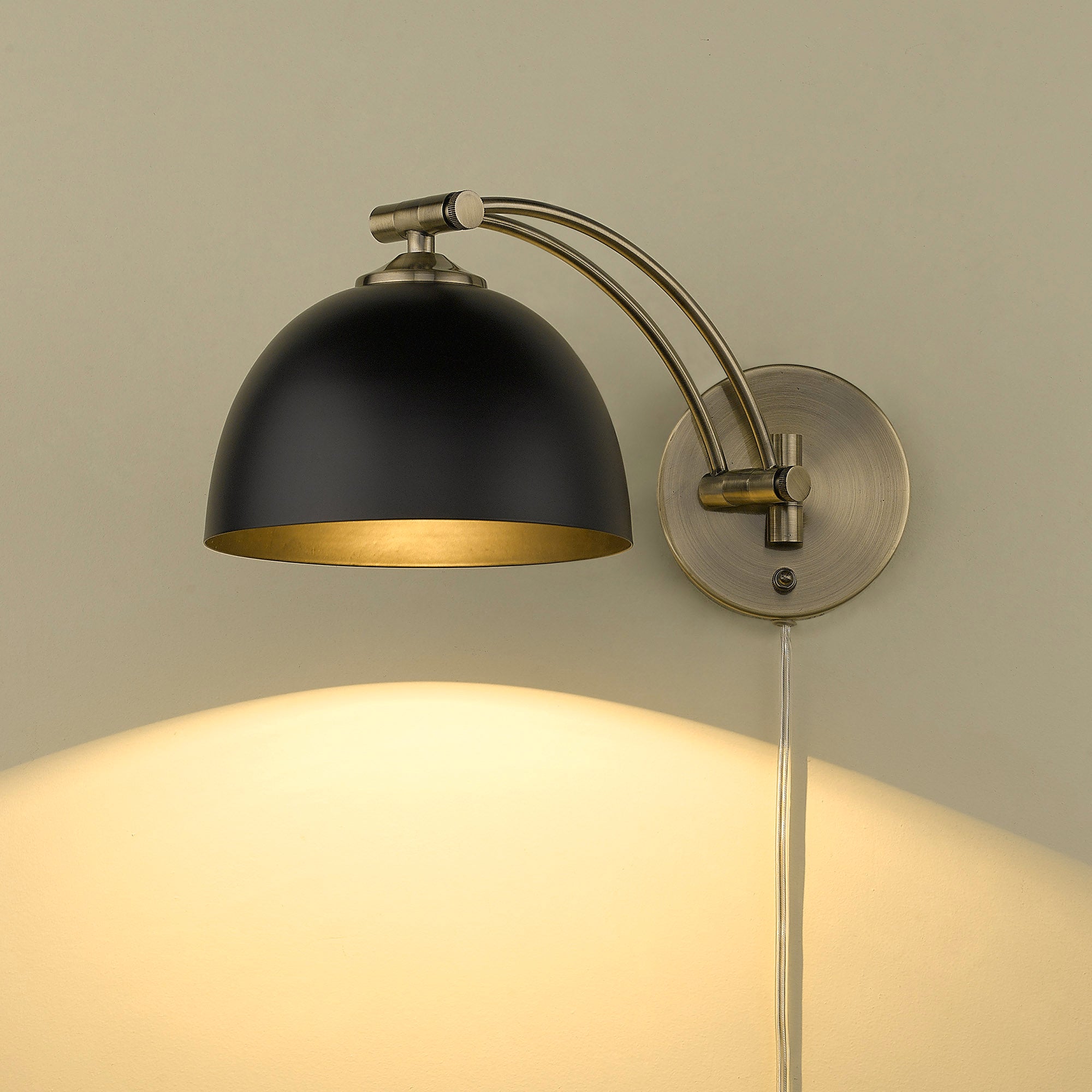 Rey 1-light Swing Arm Wall Lamp in Aged Brass and Matte Black shade, shown in a room setting - Golden Lighting