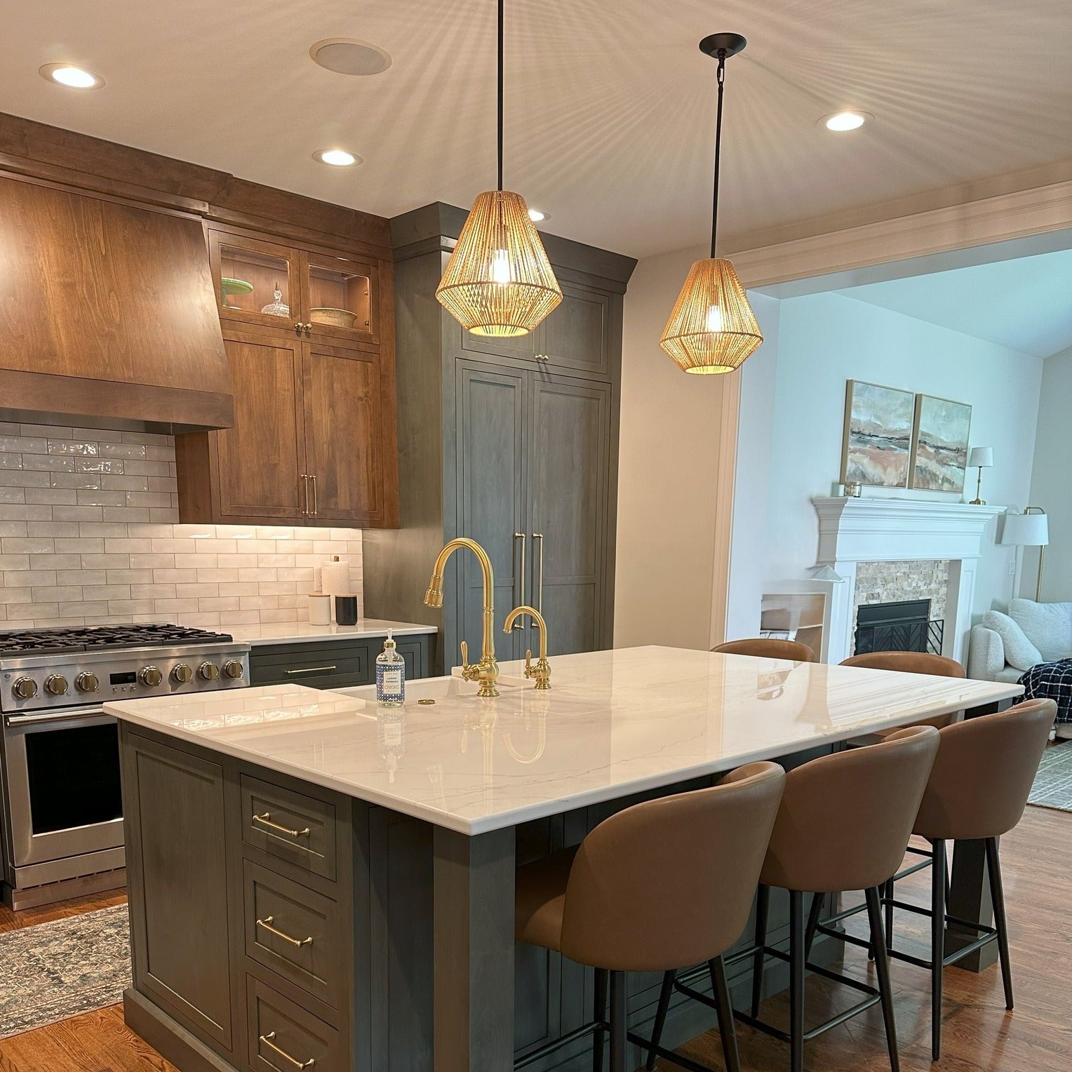 Modern kitchen with island, chairs, and a view into a living room. Two Valentina single light pendants hang over the crisp kitchen island showcasing beautiful shadow plahy on the ceiling as the light shines through the natural fibers on the wicker shades.