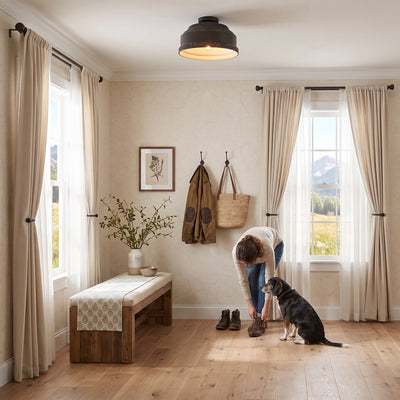 Keating 3-light Flush Mount in Antique Black Iron, AI-visualized entryway scene - Golden Lighting (with person and dog)
