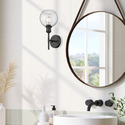 Axel 1-light Wall Sconce in Matte Black and Globe Seeded Glass, shown in a room setting - Golden Lighting