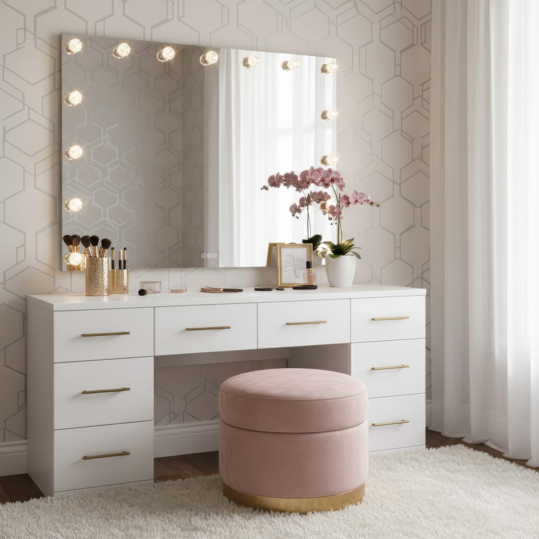 White vanity with mirror and lights, pink stool, and decorative items in a room with geometric wallpaper.